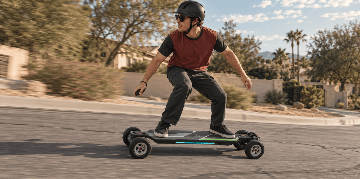 Helmeted rider on a Maxfind CYBER ULTRA electric skateboard crossing a cracked asphalt street.