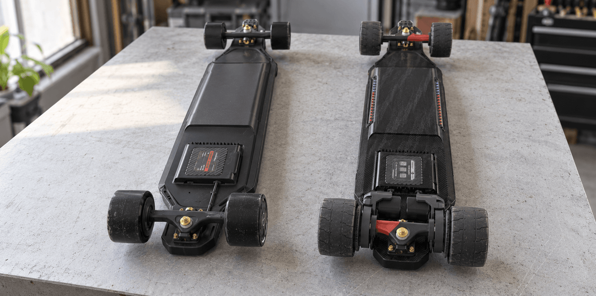 Maxfind Cyber Max LR and Cyber Max X turned upside down on a workbench to show their hub and belt drivetrains.